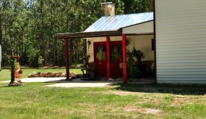 porch with red front door red columns, hanging plants, wind chimes